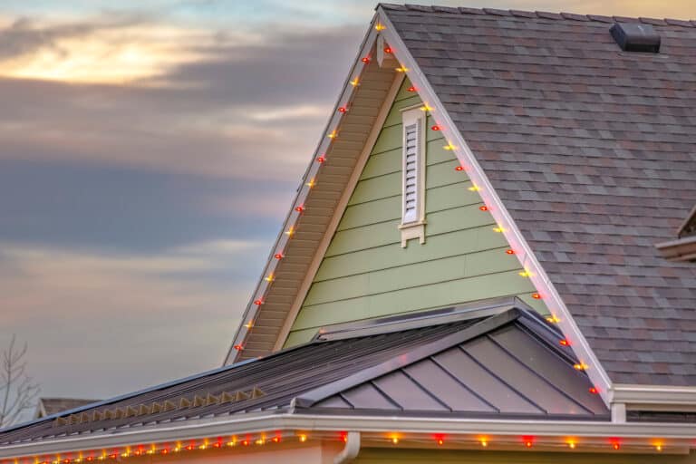 Professional Christmas light installer working safely on roofline