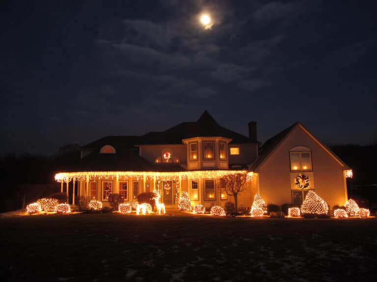 Christmas House lit up with white lights, moon in the sky